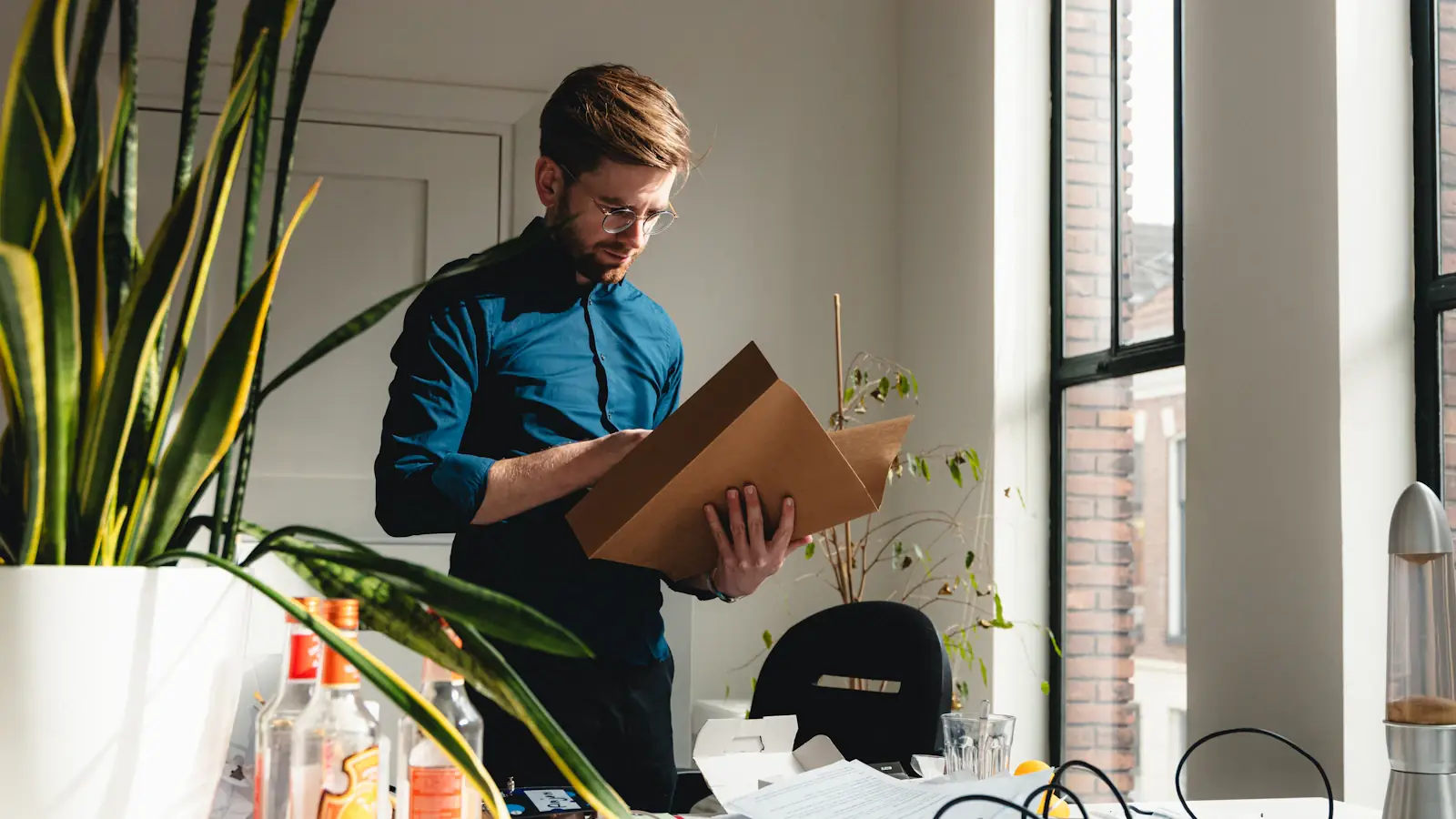 Ein Mann steht in einem hellen Büro und sieht in einen offenen Pappkarton